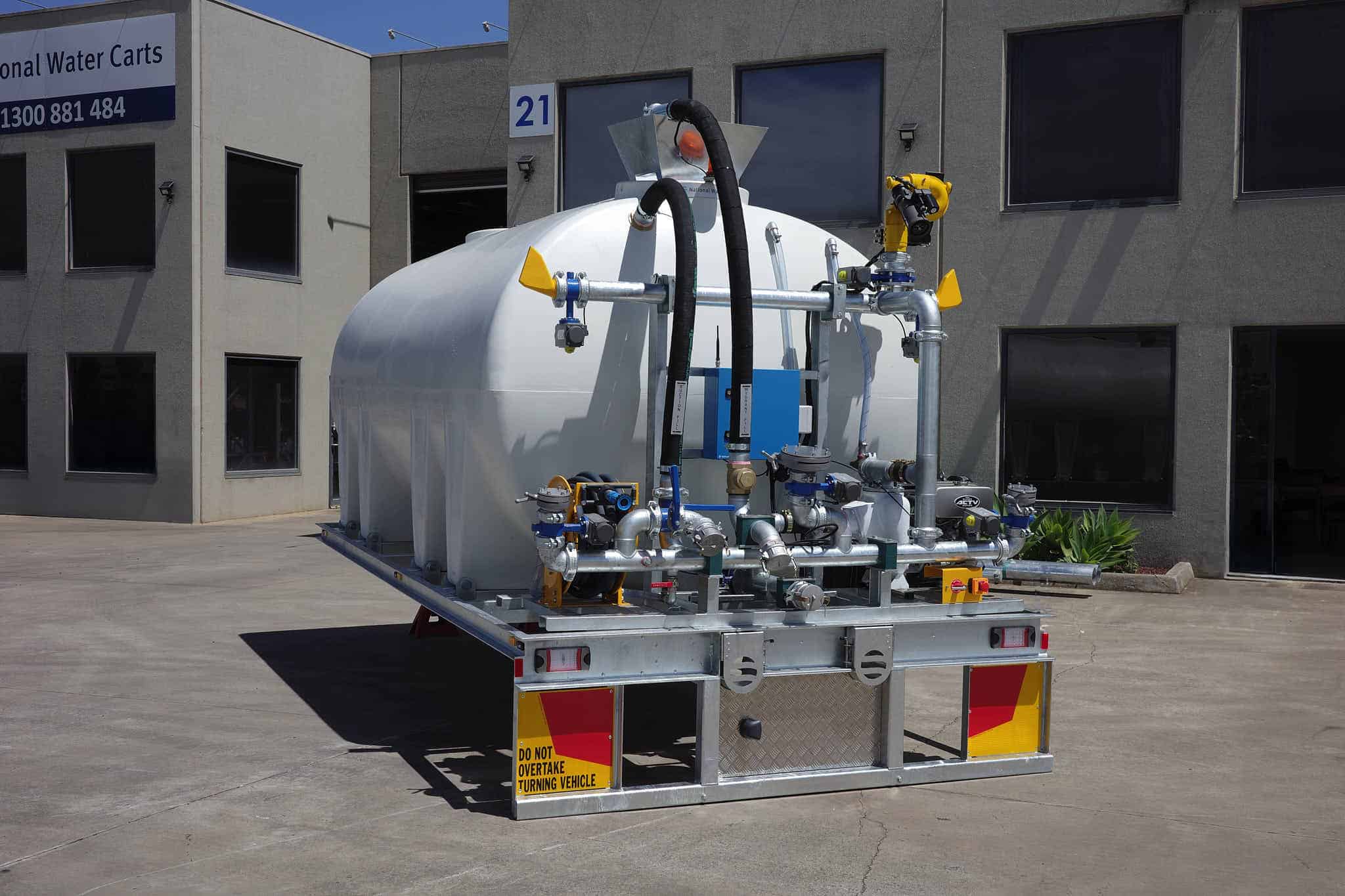 A CivMaster EXM diesel chassis chassis module is parked outside a National Water Carts facility, showing rear-mounted pipe manifold.