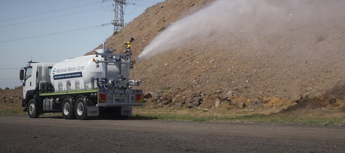 A 13,000-litre CivMaster EXM FVZ CANbus hydraulic water truck saturates an embankment using its side batter spray while in motion.